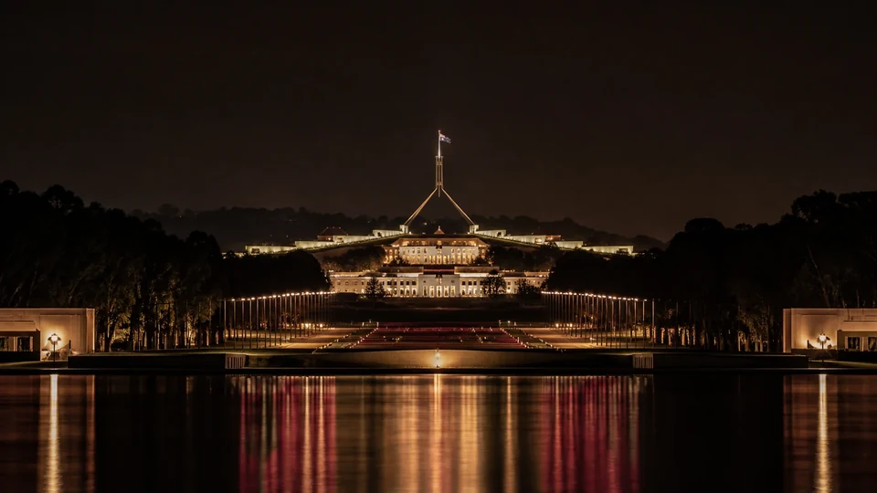 Canberra Parliament House illuminated at night across Lake Burley Griffin